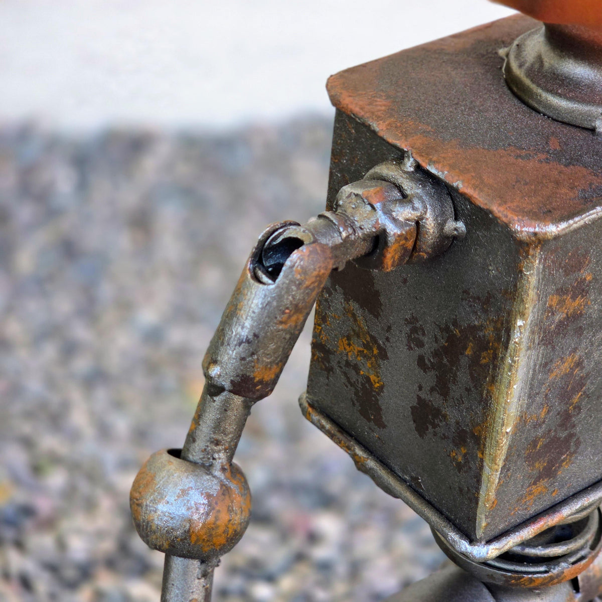 a close-up view of a rusted metal object, possibly a piece of machinery or a tool, with a large bolt or nut attached to it. The object appears to be made of metal and has a weathered, rusted appearance.