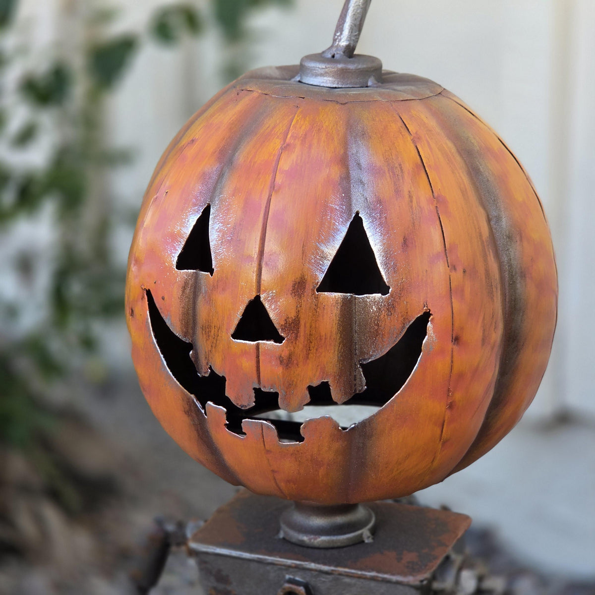 A carved pumpkin with a carved face and a metal stem is displayed in the image.